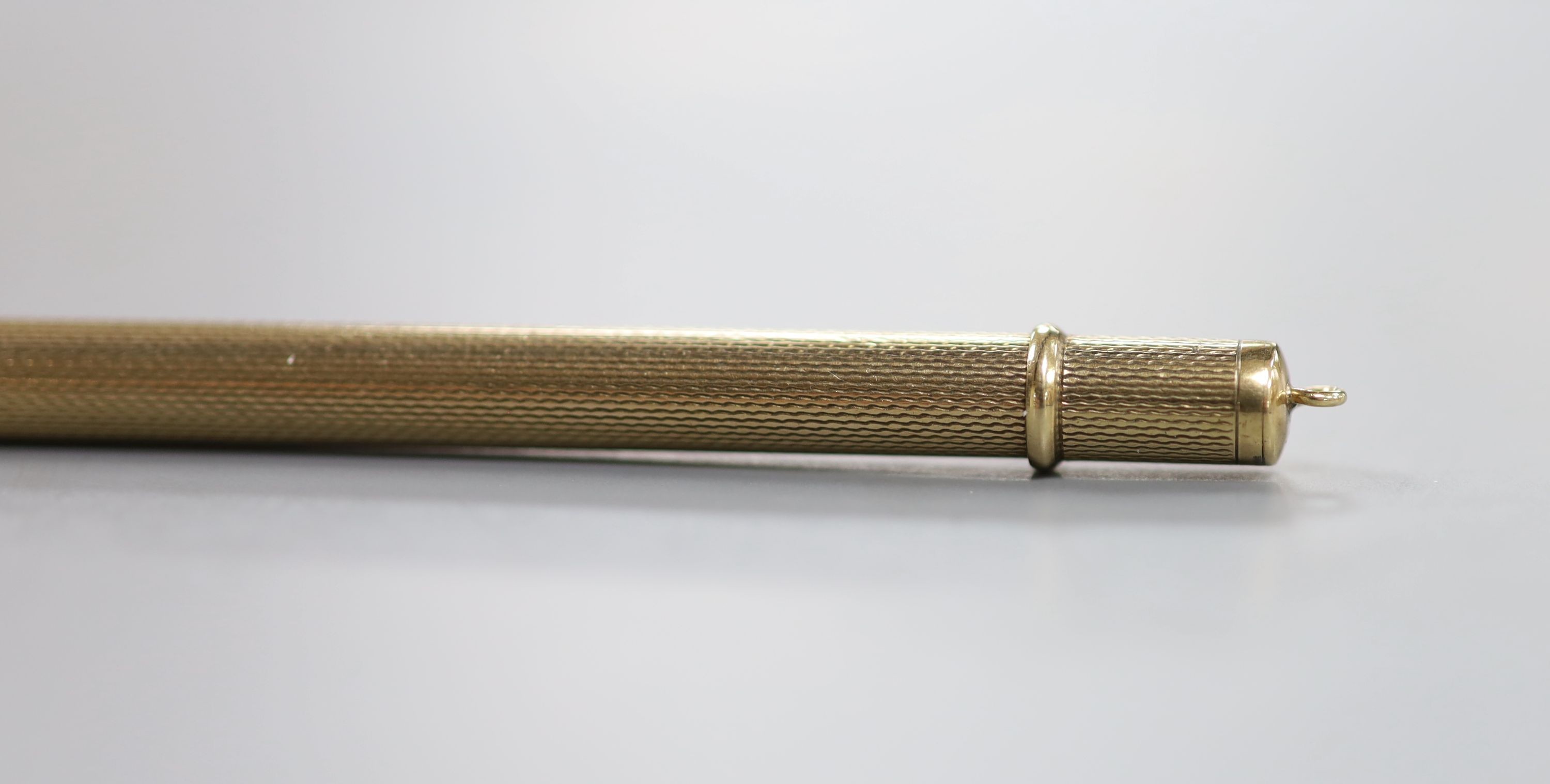 An engine turned 9ct gold cased pencil, 86mm, gross weight 10.5 grams.